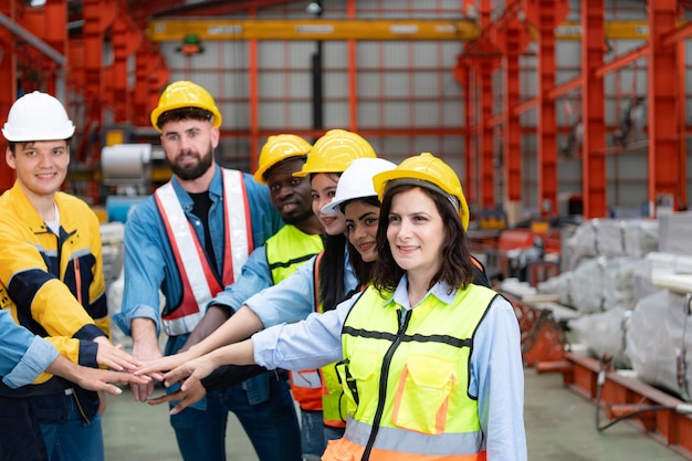 Foto grupo de trabajadores de la fábrica con cascos con las manos unidas para celebrar el éxito