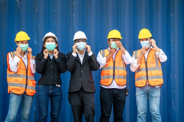 Foto grupo de trabajadores llevan máscaras de protección y cascos de seguridad en el sitio de construcción