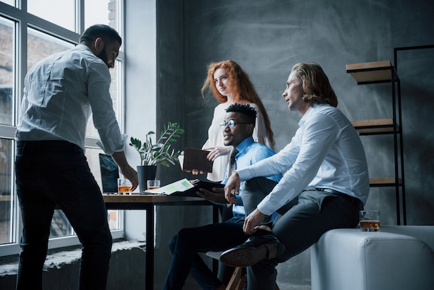 Grupo de trabajadores de oficina en ropa formal hablando de tareas y planes