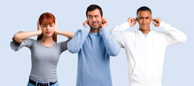 Grupo de tres amigas cubriendo ambas orejas con las manos.