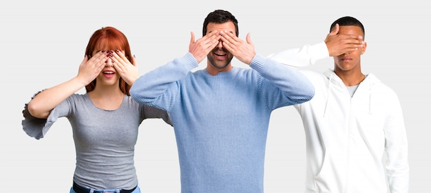 Grupo de tres amigas cubriéndose los ojos con las manos.