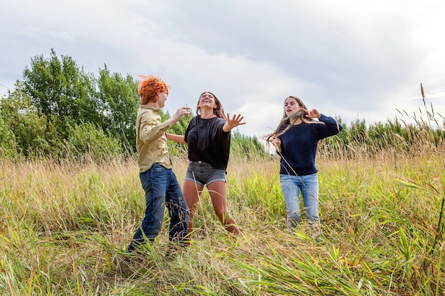 Grupo de tres amigos chico y dos chicas bailando y divirtiéndose juntos al aire libre