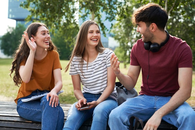 Un grupo de tres estudiantes caucásicos divirtiéndose fuera del campus universitario.