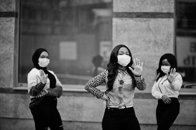 Grupo de tres jóvenes voluntarios afroamericanos con mascarilla al aire libre. Cuarentena de coronavirus y pandemia global.
