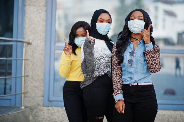 Grupo de tres jóvenes voluntarios afroamericanos con mascarilla al aire libre. Cuarentena de coronavirus y pandemia global.