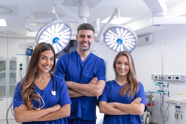 Grupo de tres médicos y enfermeras parados en un pasillo del hospital usando batas El equipo de trabajadores de la salud mira la cámara y sonríe