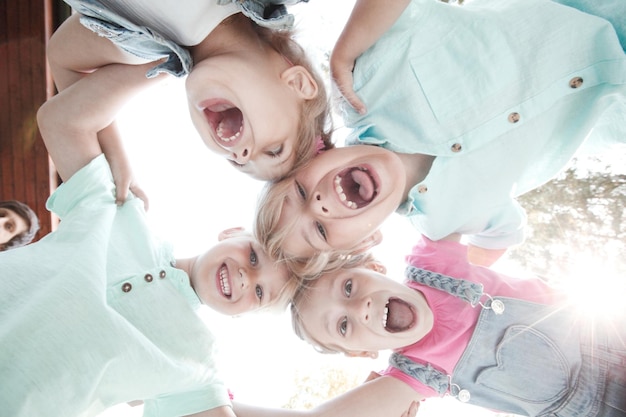 Grupo de tres niños amigos al aire libre mirando hacia abajo y sonriendo