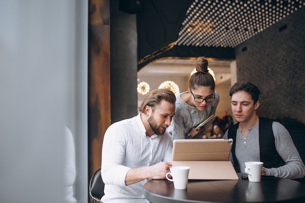 Grupo de tres personas que trabajan en un proyecto en una tableta en un café