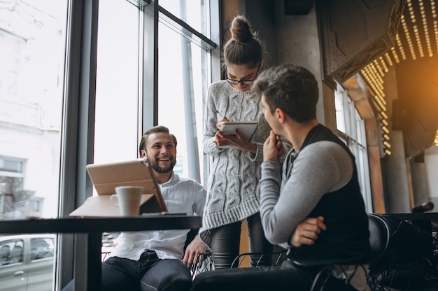 Grupo de tres personas que trabajan en un proyecto en una tableta en un café