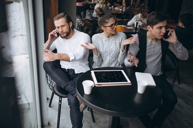 Grupo de tres personas que trabajan en un proyecto en una tableta en un café