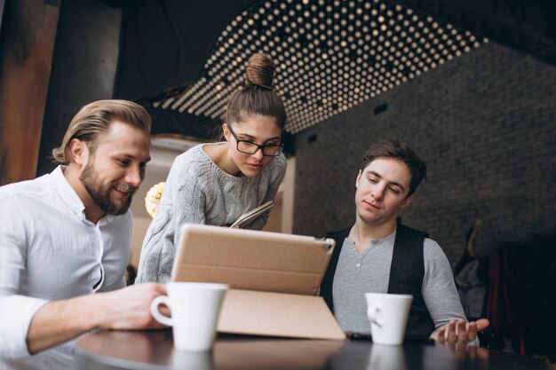 Grupo de tres personas trabajando en un proyecto en una tableta en un café
