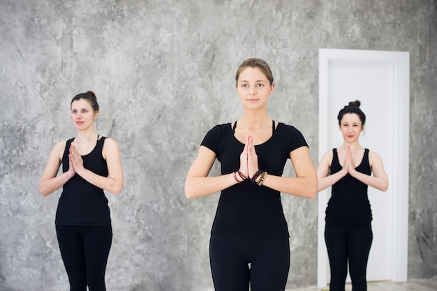 Grupo de trío deportivo joven de mujeres practicando ejercicios de yoga en el estudio