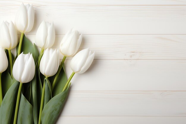 Un grupo de tulipanes blancos sobre una superficie de madera blanca.