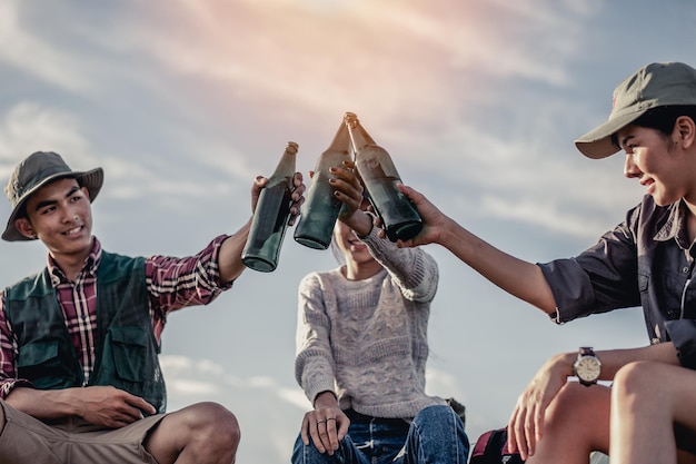 grupo de turistas tintineando botellas de cerveza en camping. concepto de aventura, viajes, turismo, amistad y personas.