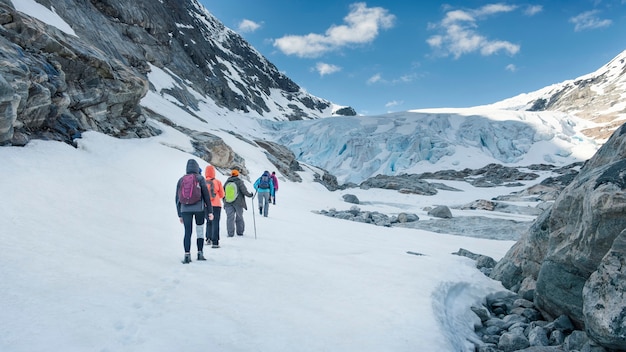 Un grupo de turistas viene al pie del glaciar en las montañas.