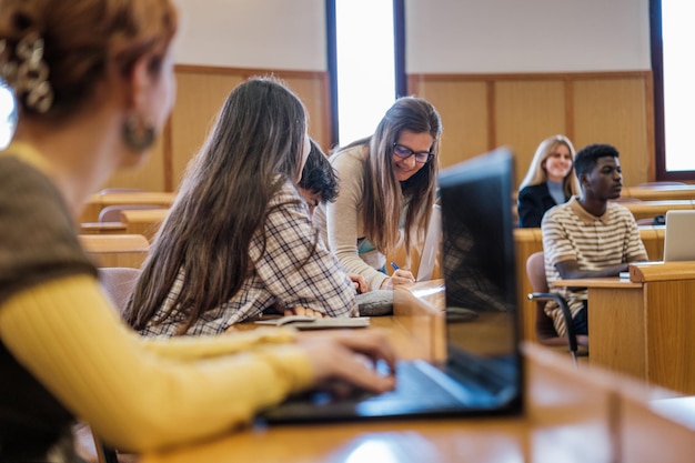 Grupo de universitarios atendidos individualmente por el profesor Foco en el profesor Concepto estudios aula universidad