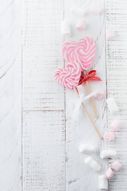 Grupo de varios dulces festivos en forma de corazón sobre fondo blanco de madera