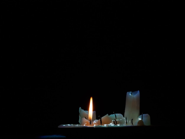 Un grupo de velas quemadas, una todavía encendida en la oscuridad.