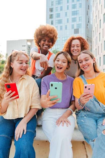 Grupo vertical de adolescentes usando un teléfono móvil mujeres jóvenes viendo sus teléfonos inteligentes femeninas