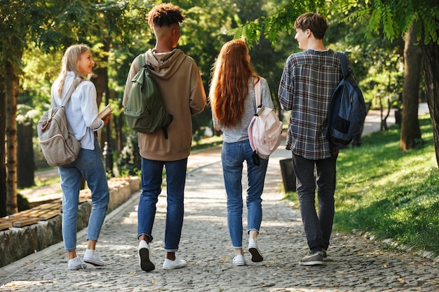 Foto grupo de vista posterior de jóvenes estudiantes con mochilas