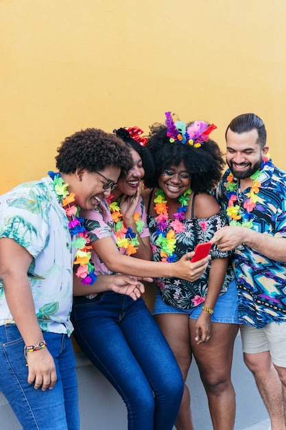 Grupos de amigos riendo y usando celulares en Carnaval