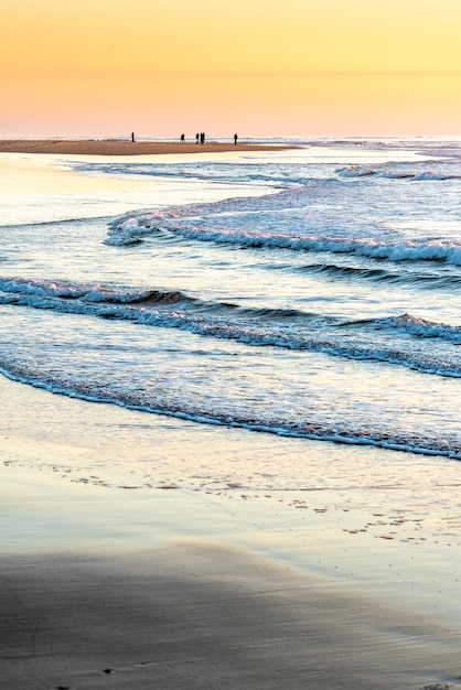 Grupos de caminantes crean siluetas que se destacan a la luz del atardecer en una playa