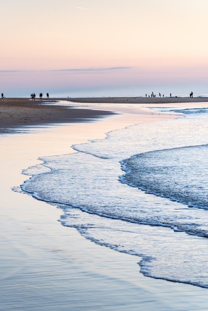 Grupos de caminantes crean siluetas que se destacan a la luz del atardecer en una playa