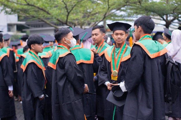 Grupos de estudantes do sexo masculino usam toga na formatura Feliz e alegre