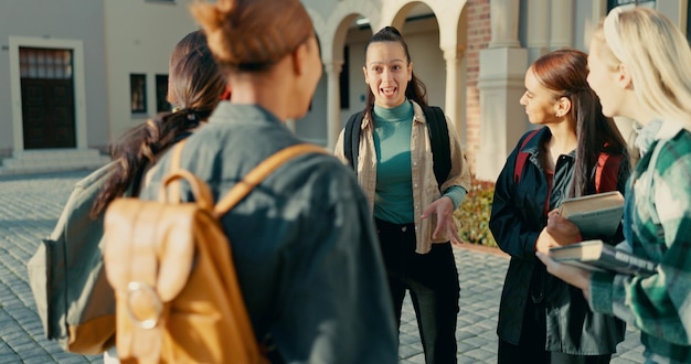 Grupos de estudantes e meninas na faculdade com conversas em círculo para conversas engraçadas fofocas universitárias ou mochilas amigos do campus e diversidade com ligação descanso de aprendizagem e feliz por bolsa de estudos