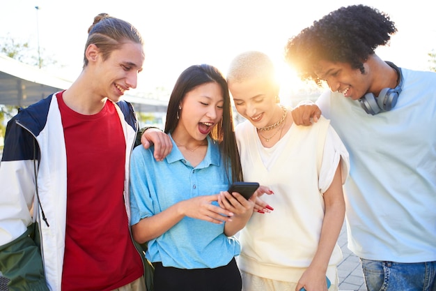 Foto grupos de jovens multirraciais usando smartphones móveis ao ar livre estão olhando para algo com um