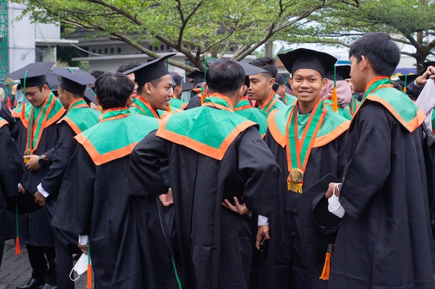 Grupos de estudiantes varones visten toga en la graduación Feliz y alegre
