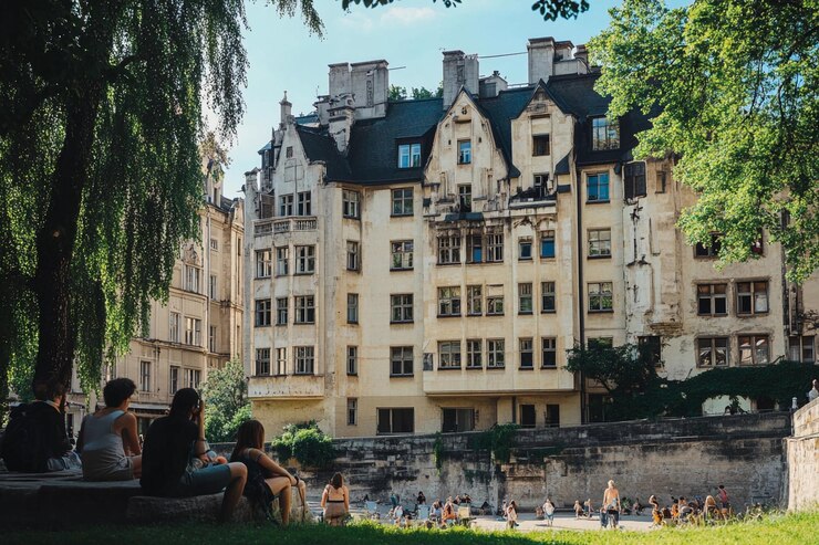 Grupos de personas disfrutan de su tiempo libre en un parque junto a la arquitectura antigua bajo un cielo despejado