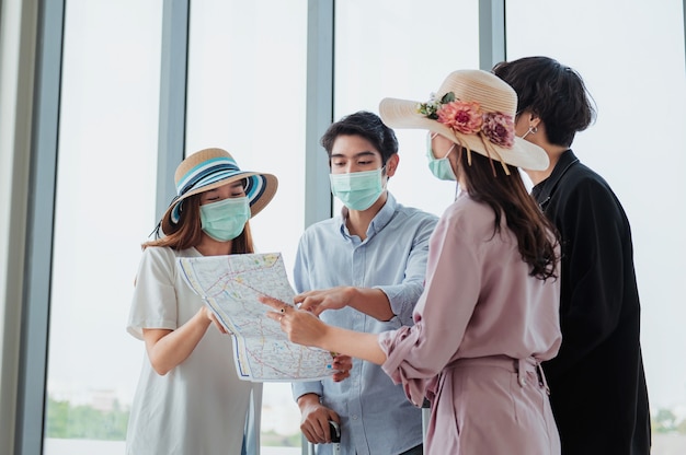 Grupos de turistas usan máscaras y miran mapas en el aeropuerto antes de su viaje.