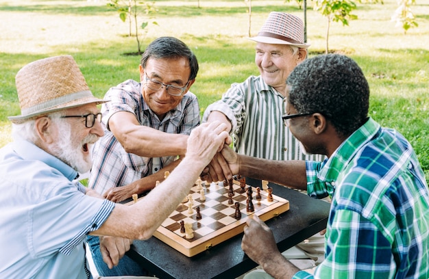 Gruppe ältere Freunde, die Schachspiel im Park spielen. Lifestyle-Konzepte zu Seniorität und drittem Alter