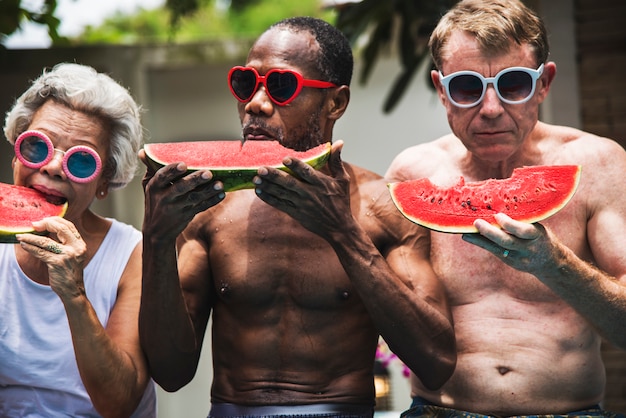 Gruppe ältere freunde, die wassermelone auf dem poolside essen