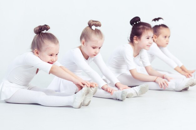 Gruppe anmutiger hübscher kleiner Ballerinas, die während des Unterrichts an einer klassischen Ballettschule üben