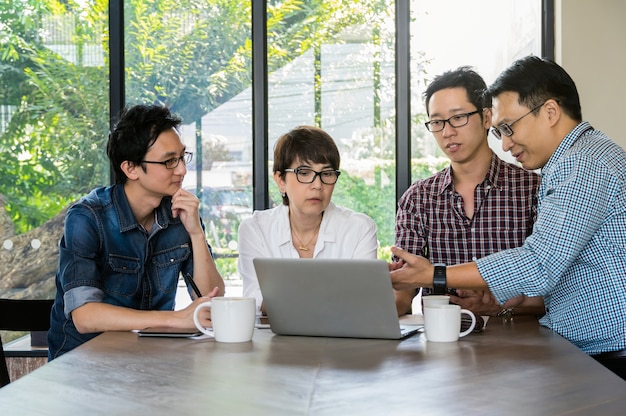 Gruppe asiatische Geschäftsleute mit zufälliger Klage treffen sich im modernen Büro