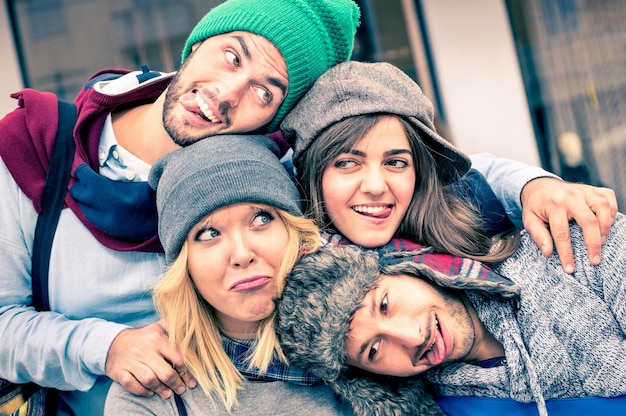 Gruppe bester Freunde, die sich im Freien mit lustigem Gesichtsausdruck und modischer Kleidung selbst machen