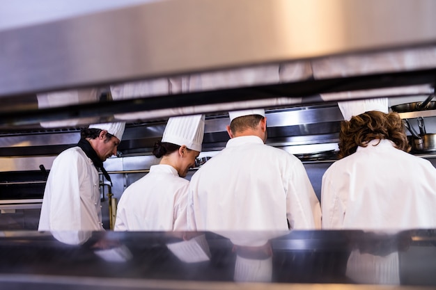 Gruppe Chefs in der weißen Uniform beschäftigt zur Zubereitung des Lebensmittels