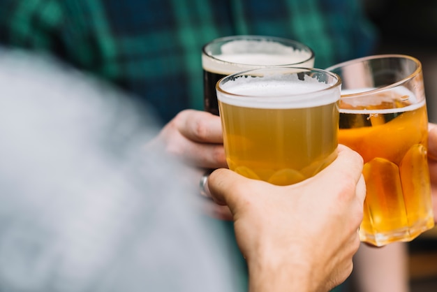 Gruppe der Hand des Freundes, die mit Glas Bier zujubelt