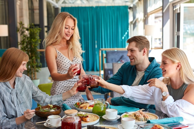 Gruppe der jungen kaukasischen Leute, die Geburtstag mit klirrendem Glas des Getränks feiern