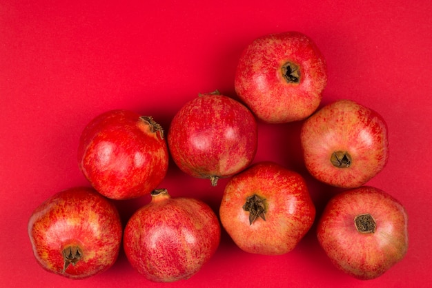 Gruppe des süßen Granatapfels auf rotem Hintergrund.
