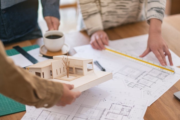 Gruppe eines Architekten, der die Skala eines Massenmodells auf dem Tisch im Büro arbeitet und misst