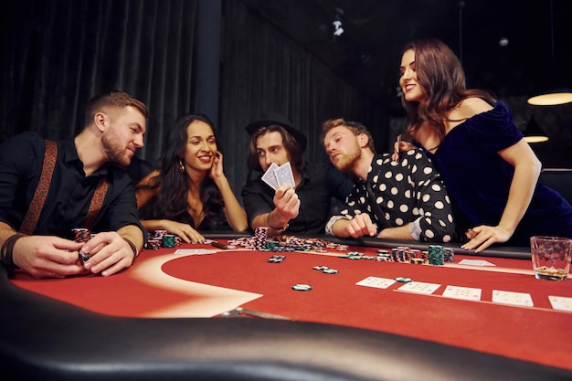 Gruppe eleganter junger Leute, die zusammen Poker im Casino spielen.