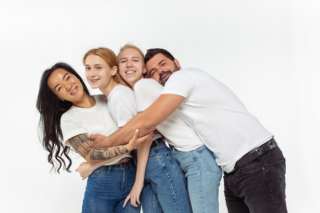 Gruppe entzückender multiethnischer Freunde, die Spaß isoliert über weißer Wand haben