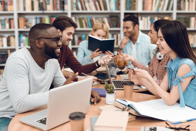 Gruppe ethnische multikulturelle Studenten, die bei Tisch sitzen.