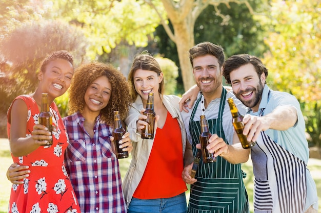 Gruppe Freunde, die Bierflasche im Park zeigen