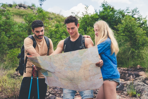 Gruppe Freunde, die mit den Rucksäcken betrachten die Karte wandern, finden Richtungen zur Gebirgsreise