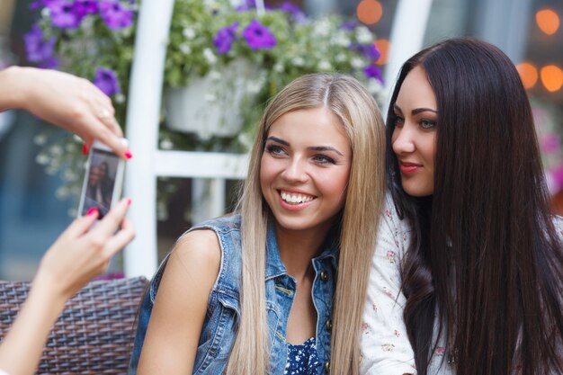 Gruppe Freundinnen, die ein selfie Foto an der beweglichen Kamera ein Lächeln machen. Hübsche Frauen, die Spaß am Café haben. Junge Mädchen lachen