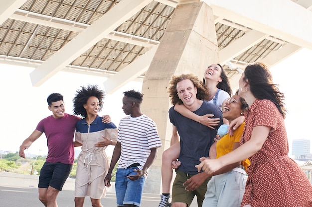 Gruppe freundlicher multiethnischer Freunde, die Spaß haben, junge Studenten außerhalb der Universität umarmen